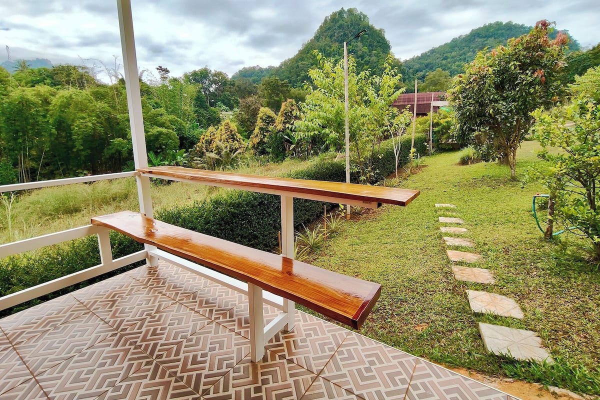 Un espace extérieur abrité, doté d’un banc en bois et d’un sol carrelé aux motifs décoratifs.