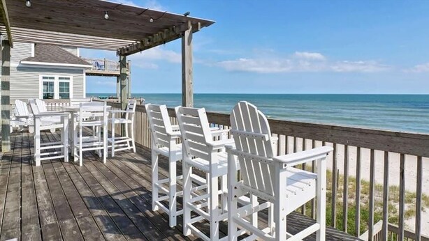 A wooden deck with white chairs and a small table, overlooking a beach. - Surfer's Delight - Amazing 6 BR Oceanfront Home in Hampton Colony (North Topsail Beach)