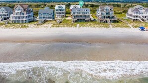A beachfront property with multiple houses, a sandy beach, and waves crashing onto the shore. - Surfer's Delight - Amazing 6 BR Oceanfront Home in Hampton Colony (North Topsail Beach)