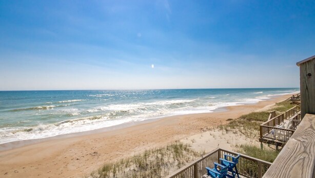 A beach view with a wooden deck and blue chairs. - Son Burn - 3BR Oceanfront Turtle Cove Townhouse (Surf City)