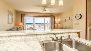 A kitchen with a large window, a ceiling fan, and a view of the ocean. - Son Burn - 3BR Oceanfront Turtle Cove Townhouse (Surf City)