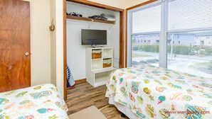A bedroom with two beds, a TV, a wardrobe, and a window with blinds. - Son Burn - 3BR Oceanfront Turtle Cove Townhouse (Surf City)