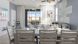 A dining area with a glass table, wooden chairs, and a modern chandelier.