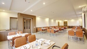 A spacious conference room with multiple tables and chairs, equipped with water bottles and cutlery. - Buddha Residency Sravasti by DD (Ikauna)