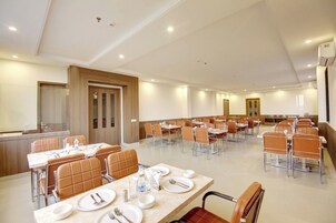 A spacious conference room with multiple tables and chairs, equipped with water bottles and cutlery.