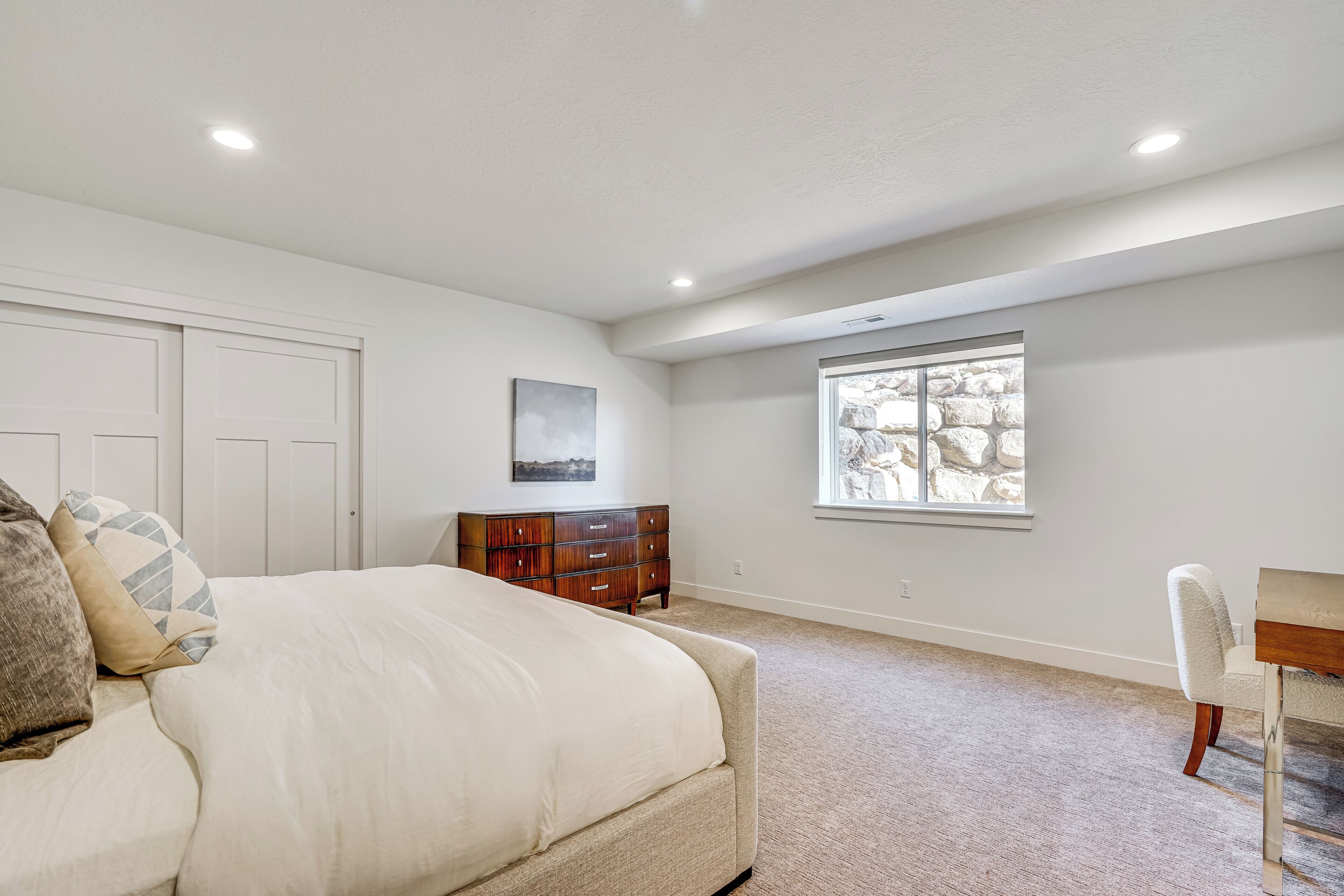 A bedroom with a bed, dresser, and window.