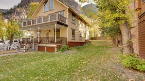Ein zweistöckiges Haus mit Balkon, einer Veranda und einem Berg im Hintergrund.