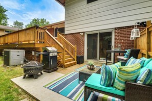 A backyard with a wooden deck, a grill, a fire pit, outdoor furniture, and a patio area.