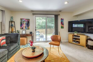 A living room with a sofa, a coffee table, a TV, and a sliding glass door leading to an outdoor area.