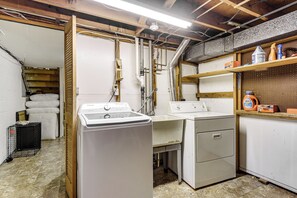 A laundry room with stacked linens, a washing machine, a dryer, and a pegboard with cleaning supplies.