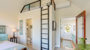 A bedroom with a bed, a nightstand, a lamp, a ladder, and a bathroom visible through an open door. - Steps to Sutter Creek: Chic Wine Country Cottage (Sutter Creek)