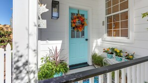 A white house with a turquoise door, a white picket fence, and a porch with potted plants. - Steps to Sutter Creek: Chic Wine Country Cottage (Sutter Creek)