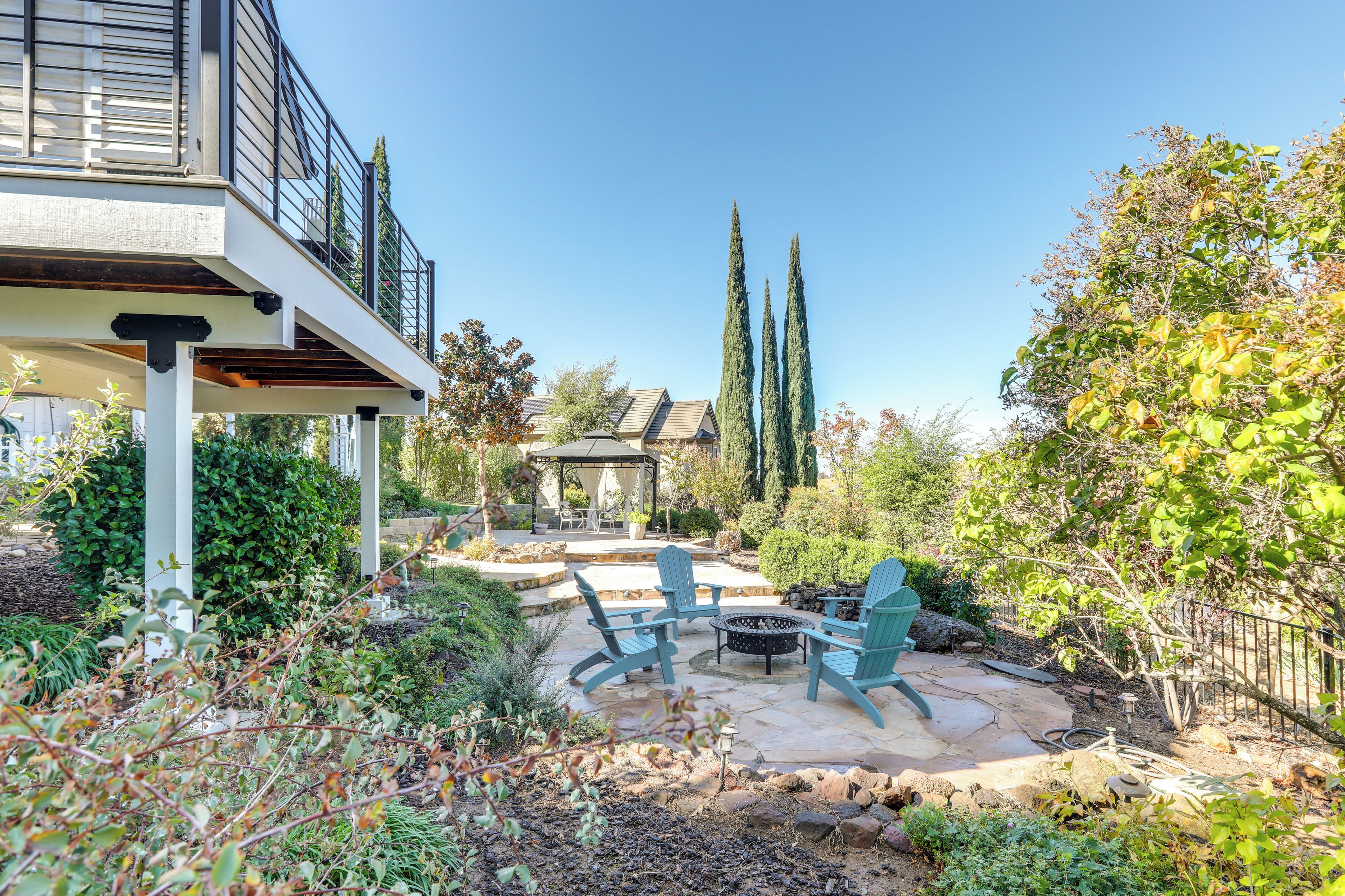 A patio area with outdoor furniture, a pergola, and a view of the surrounding garden and trees.