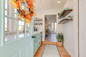 Una cocina con armarios color turquesa, una ventana con vistas y un pasillo que conduce a un comedor.