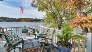 Una terraza con mobiliario exterior, una bandera y vistas a un lago.