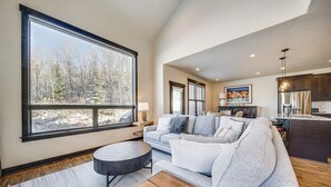 A spacious living area with a large window, a sofa, a coffee table, and a kitchen area with a refrigerator and cabinets. - 8 Mi to Keystone Resort: Mtn-view Townhome (Silverthorne)