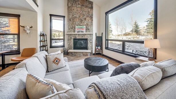 A spacious living room with a stone fireplace, large windows, and a cozy seating area. - 8 Mi to Keystone Resort: Mtn-view Townhome (Silverthorne)