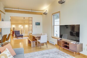Ein modernes Wohnzimmer mit Esstisch aus Holz, einer Couch und einem Fernseher.