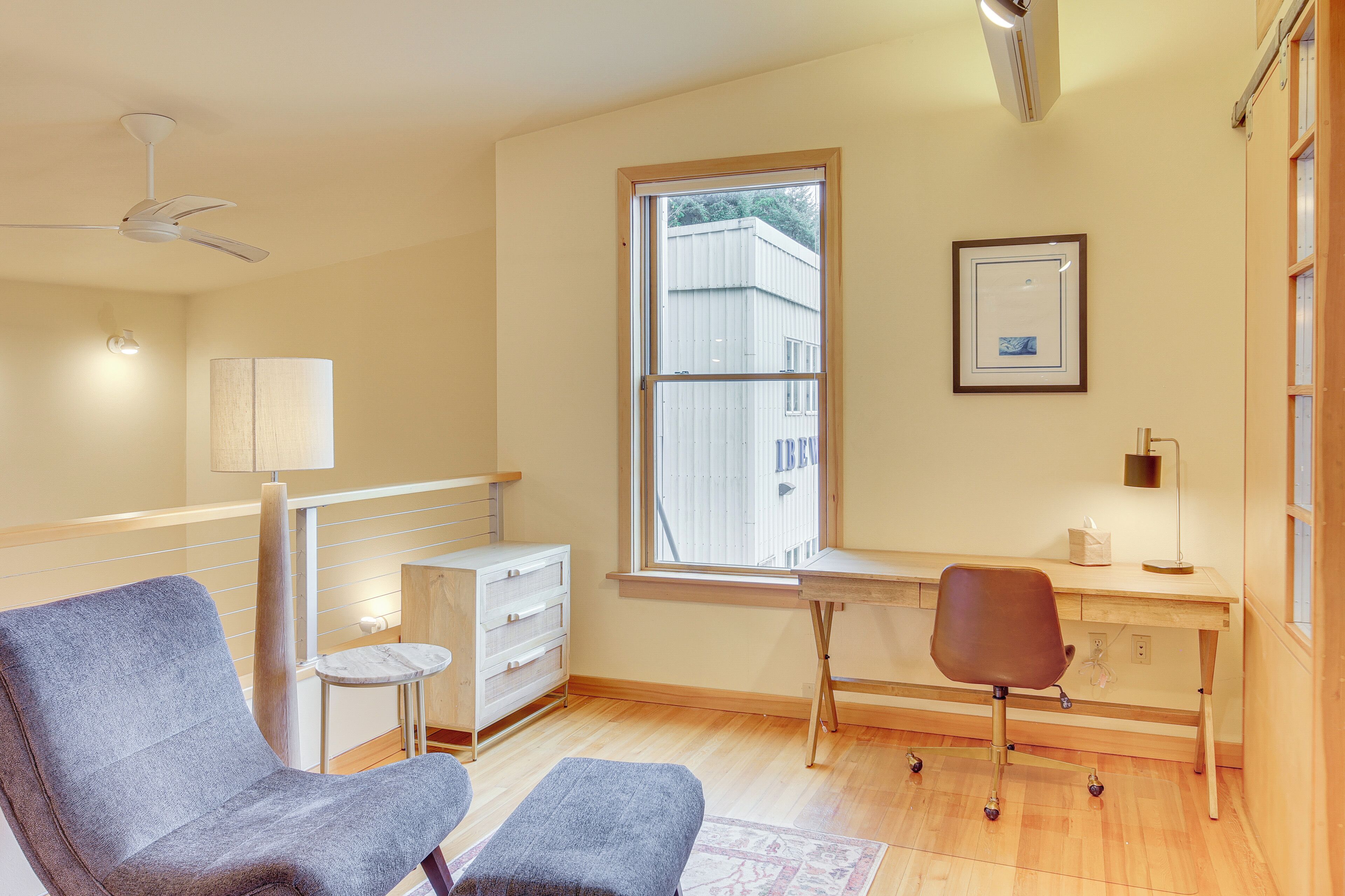 A modern room with a desk, two chairs, a small side table, a lamp, and a ceiling fan.