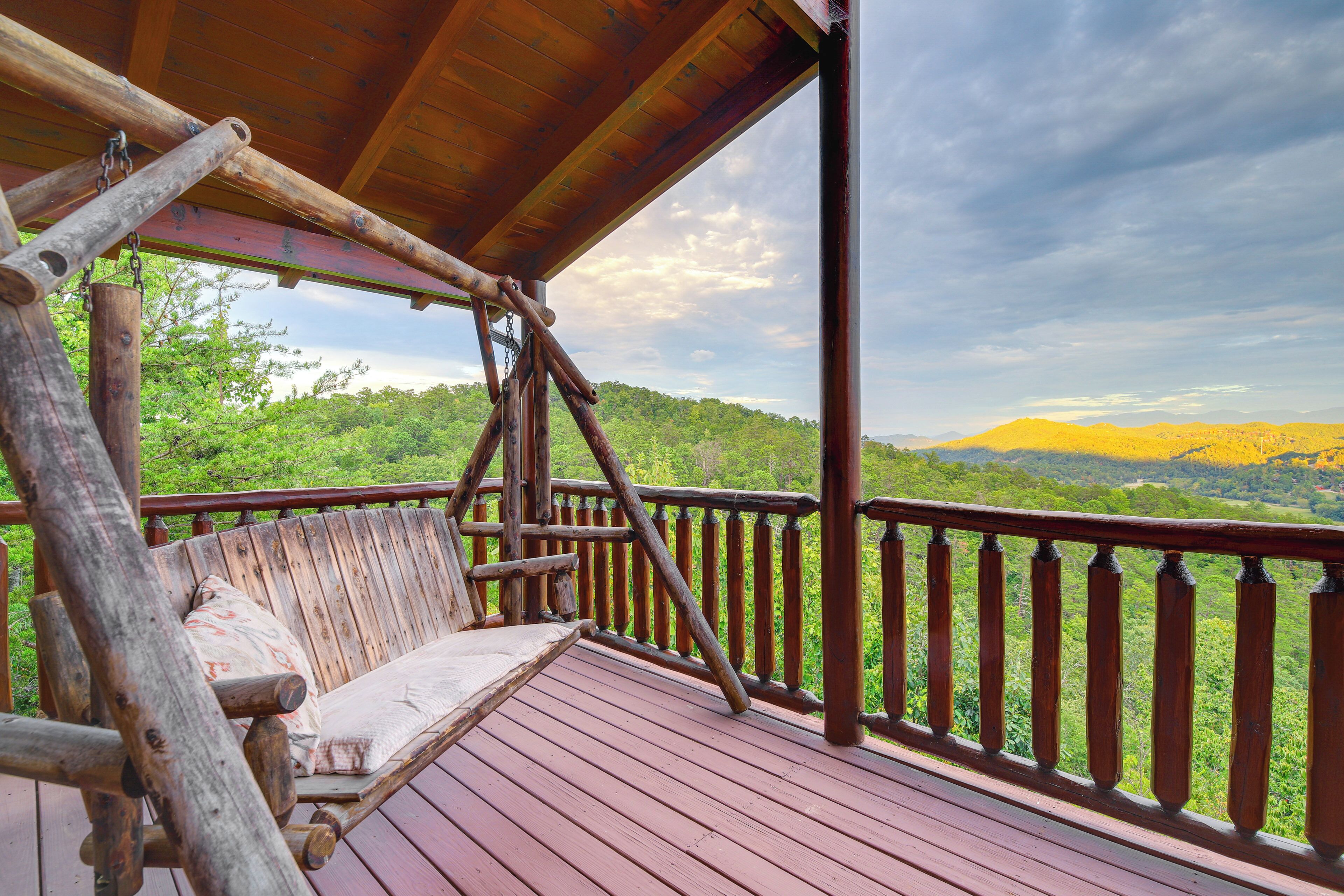 A wooden deck with a bench and a view of a forested landscape.