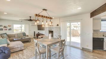 A spacious living area with a fireplace, a dining table, and a kitchen in the background.
