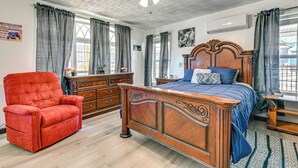 A bedroom with a wooden bed, a red armchair, and a dresser. - Bonnieville Farmhouse on 69 Acres w/ Porch! (Bonnieville)