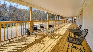 A covered porch with wooden railings, metal chairs, and a glass table. - Bonnieville Farmhouse on 69 Acres w/ Porch! (Bonnieville)