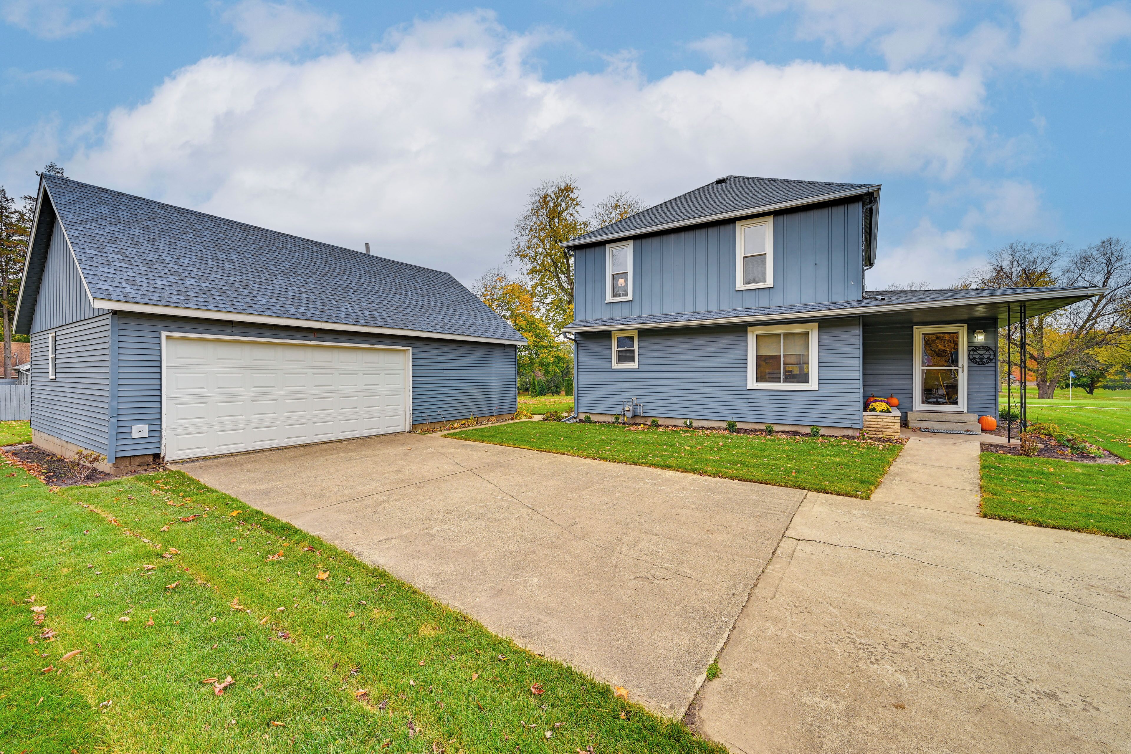 A two-story house with a garage, a front porch, and a well-maintained lawn.