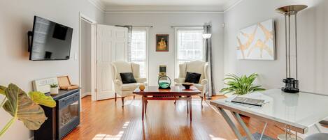 A living room with a fireplace, a television, a glass coffee table, and two armchairs.