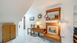 Ein Flur mit einem Holzkasten, einem Schreibtisch mit Lampe, einem Spiegel und einem gerahmten Bild an der Wand.