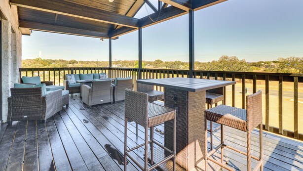 Une terrasse extérieure couverte, aménagée avec des meubles en osier et offrant une vue sur le paysage.