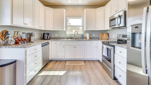 Une cuisine moderne avec des meubles blancs, des appareils en acier inoxydable et un plan de travail en granit.