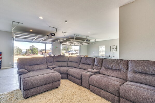 A modern living room with a sectional sofa, a large window, and a garage door.
