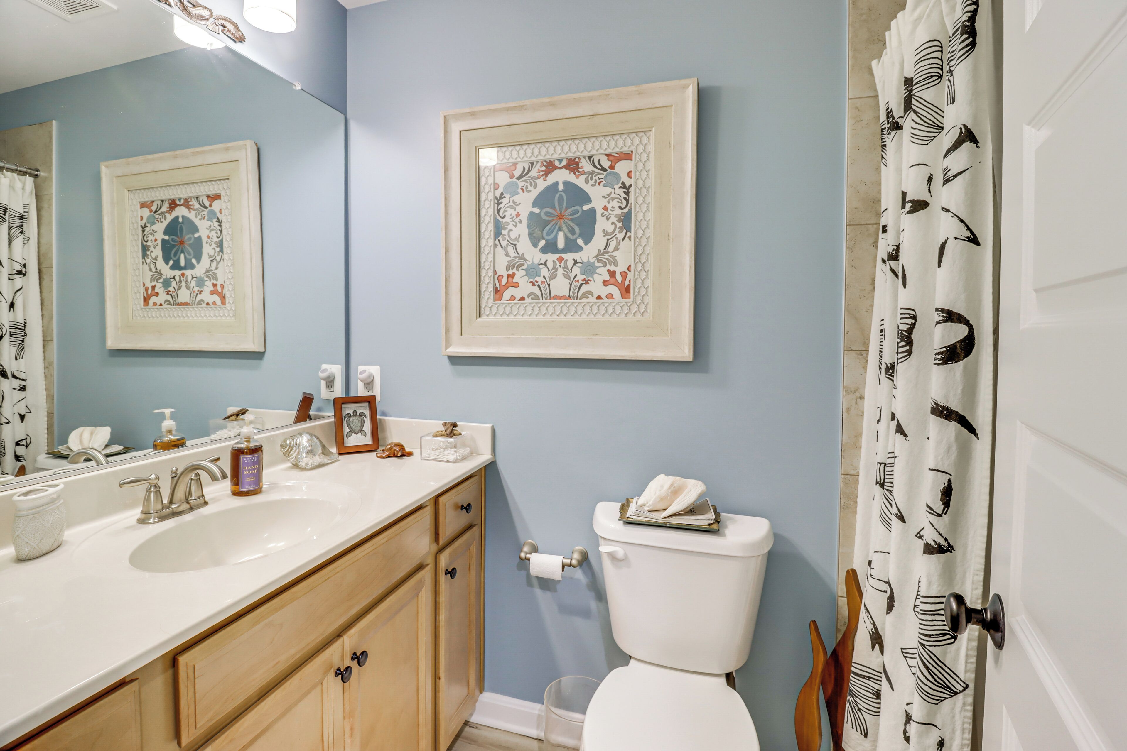Une salle de bain avec un lavabo, des toilettes et une œuvre d’art encadrée au mur.