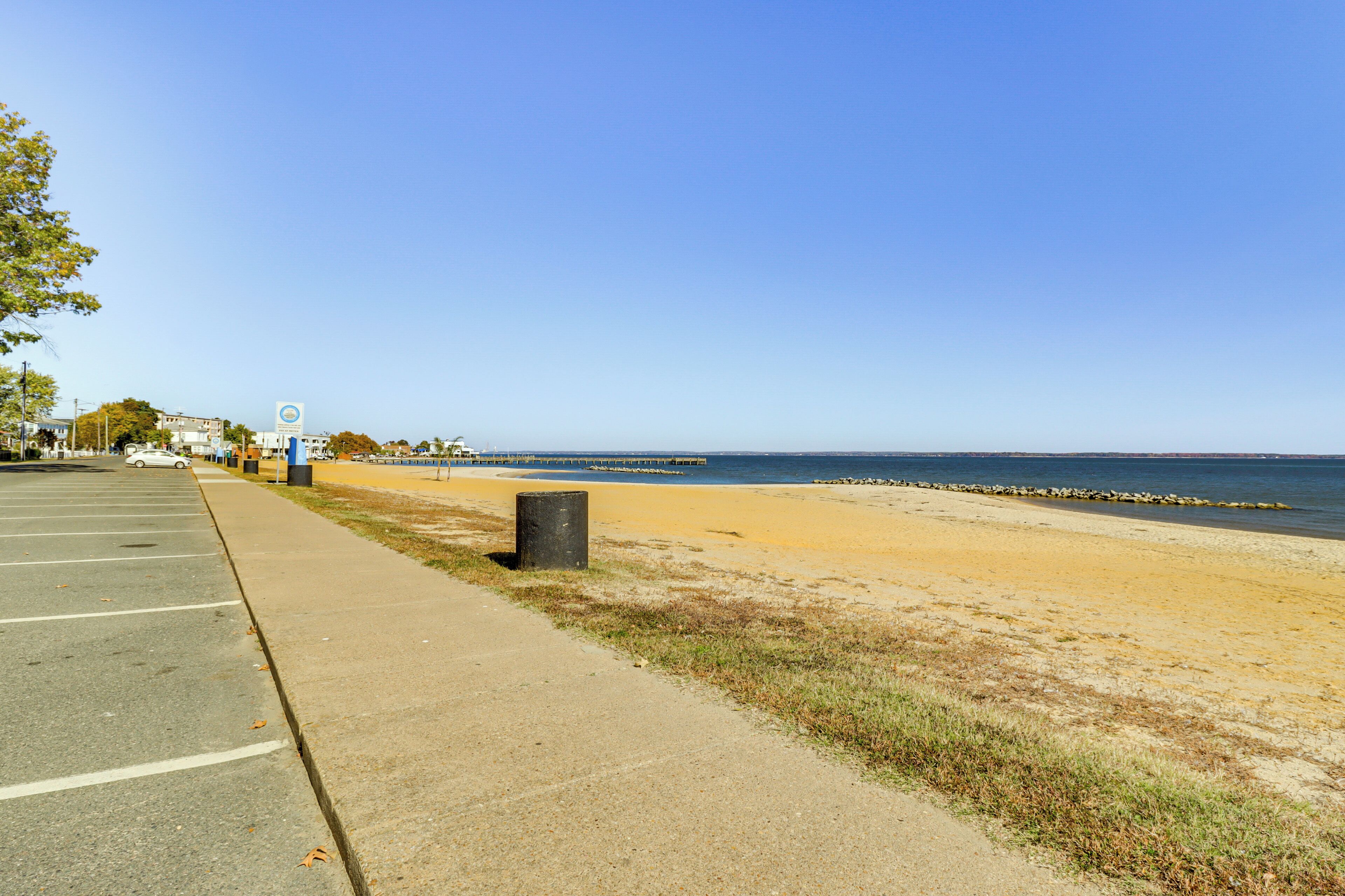 A parking lot adjacent to a beach with a clear sky.