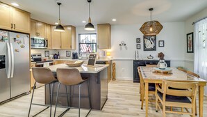 Une cuisine moderne avec des meubles en bois, des appareils en acier inoxydable et un îlot central doté de tabourets de bar.