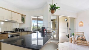 A modern kitchen with a large island, white cabinets, and a view to the living area. - Stunning Resort Apartment with Gym and Pool Access (Westcourt)