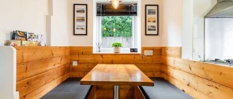 A cozy corner with a wooden bench, a table, and a hanging light fixture.