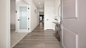 A hallway with a wooden floor, white walls, and doors with frosted glass panels.