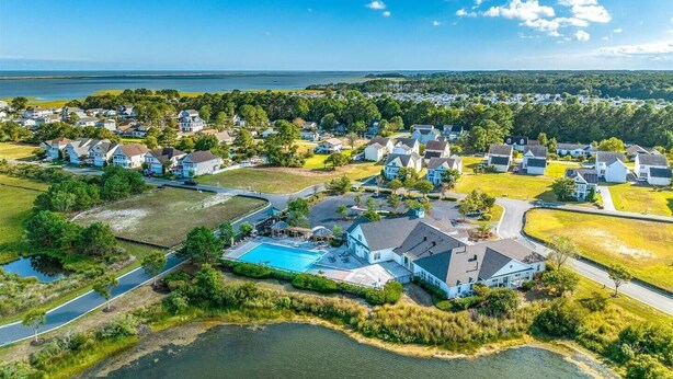 An aerial view of a residential area with houses, a swimming pool, and a lake.