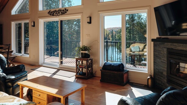 A spacious living room with large windows, a fireplace, and a TV.