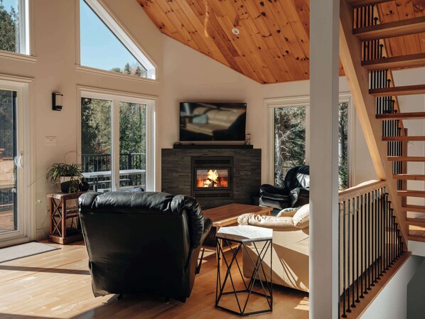 Una sala de estar moderna con chimenea, sofá de cuero y televisor montado encima.