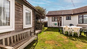 A wooden cabin with a patio area, including a bench and a table with chairs. - Host Stay Cransley (Great Yarmouth)