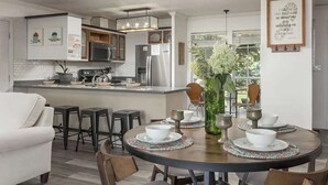 A modern kitchen with a central island, bar stools, and a dining table set for six with white plates and silverware. - The Brow House with Stunning Views! Sunsets (Lookout Mountain)