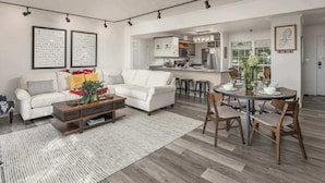 A spacious living room with a white sofa, a coffee table, and a dining area with a round table and chairs. - The Brow House with Stunning Views! Sunsets (Lookout Mountain)