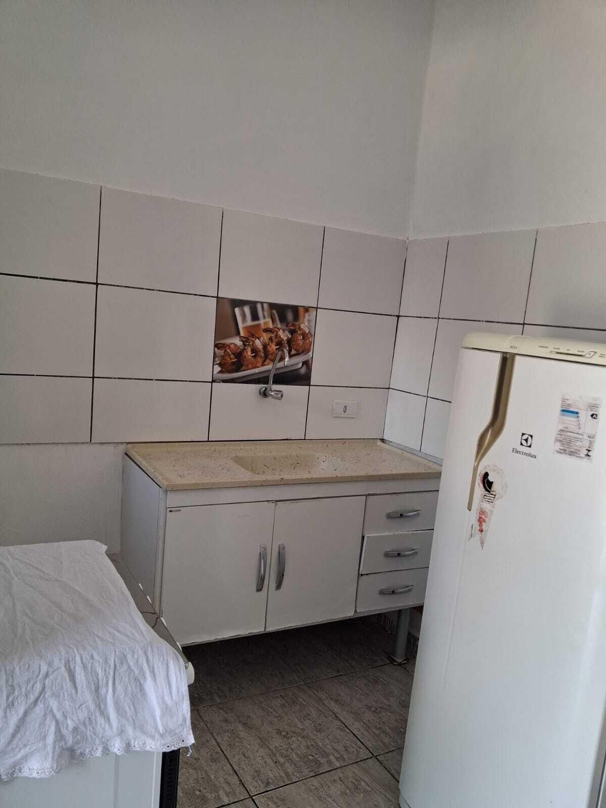 Una pequeña cocina con armarios blancos, un lavabo y un refrigerador.