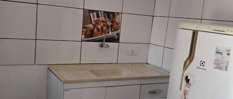 A small kitchen with white cabinets, a sink, and a refrigerator.
