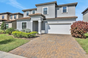A modern two-story house with a brick driveway, a garage, and a well-maintained lawn. - 209mcv - Balmoral Resort 4 Bedroom Home (Haines City)