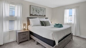 A bedroom with a bed, nightstand, and a painting on the wall. - 209mcv - Balmoral Resort 4 Bedroom Home (Haines City)