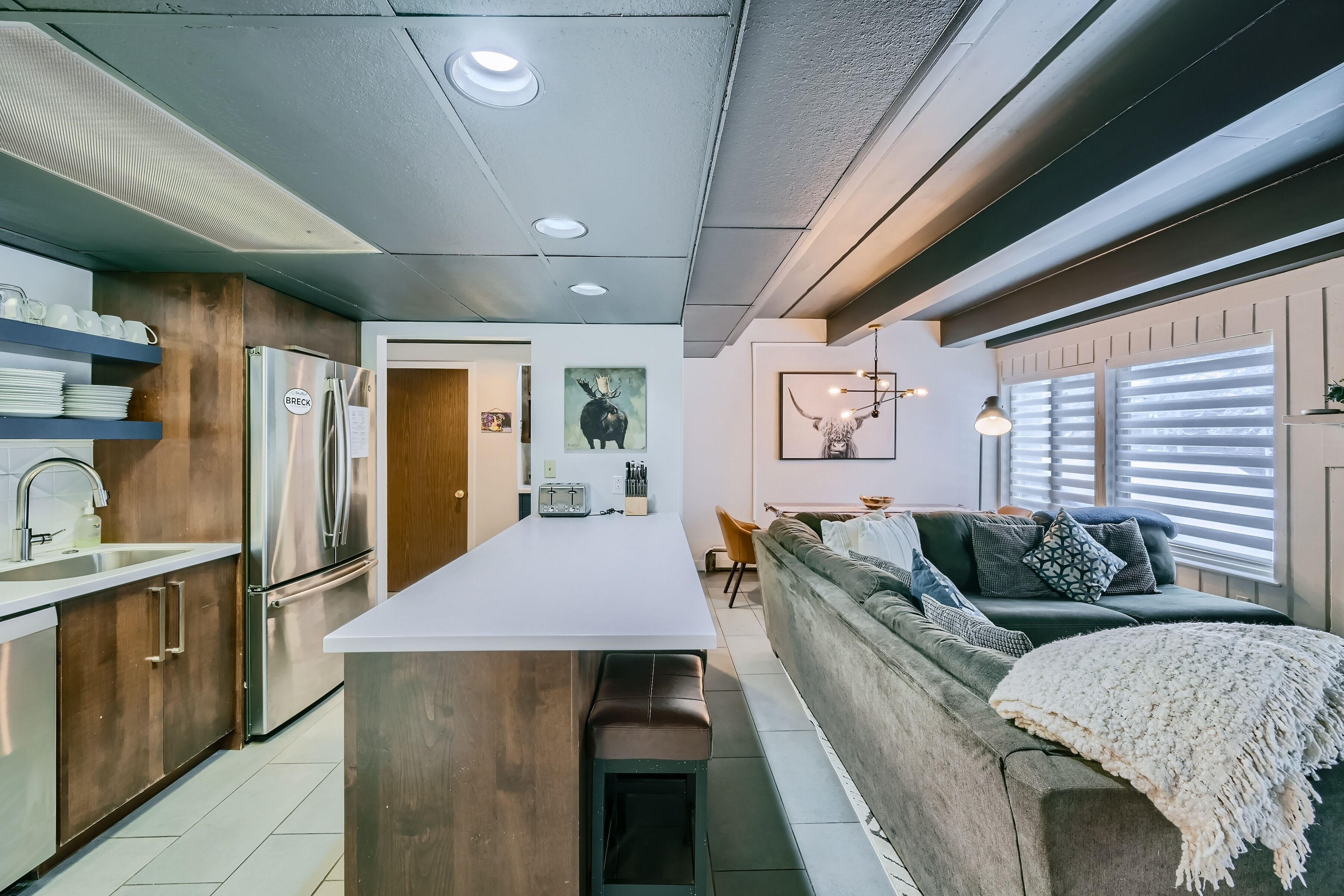 A modern kitchen with a central island, wooden cabinets, and a stainless steel refrigerator.